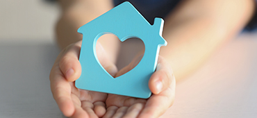 Child holding figure in shape of house, closeup. Adoption concept